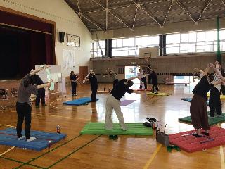 体育館で講師の指導のもとストレッチを行うPTAの人たちの写真