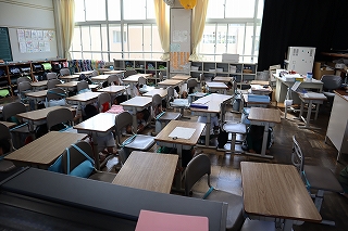 避難訓練で机の下に隠れ静かにしている生徒たちの写真