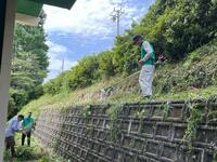 校舎西側の植え込みの雑草を取り除いている男性の写真