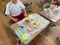 椅子に座っている児童の机の上に給食と、歯ブラシ・コップが置かれている写真