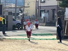 帽子を被った複数の体操服姿の児童達が両腕を振りながら走っている写真