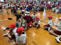 体育館のような所で沢山の児童達が座っており楽しそうにゲームを行っている写真