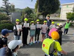 帽子をかぶった児童達が横並びになって他の児童に呼び掛けを行っている写真