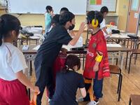 児童がヘッドフォンのようなものを身に付けている写真