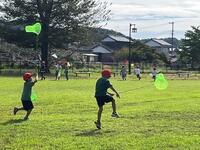 公園内で帽子を被った児童達が網を持って虫を捕まえようとしている写真