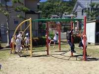 公園にある遊具で複数の児童達がぶら下がったりしながら遊んでいる写真