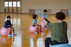 体育館でバランスボールに乗り、体幹を鍛えている生徒たちの写真
