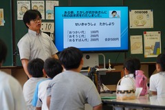 校長先生がモニターを使い、生徒たちに道徳題材の説明をしている写真