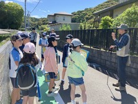 民家の立ち並ぶ中で野鳥を探している生徒たちの写真