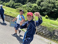 シマヘビの抜け殻を手にピースサインで記念撮影をする生徒の写真