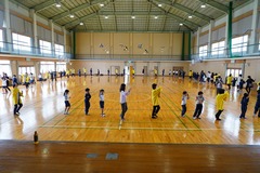 体育館で輪になって萩音頭を踊っている生徒と会員の方たちの写真