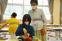 茶道の道具の使い方を教えてもらっている子供の写真