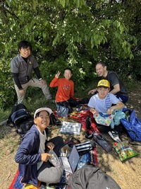 山頂でお弁当を食べている大人と子供たちの写真