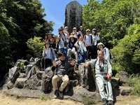 山頂で記念写真を撮っている大人と子供たちの写真