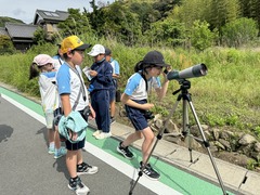 望遠鏡のピントを合わせている子供の写真