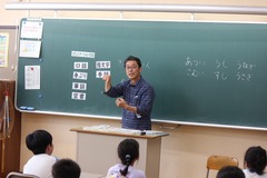 豊川市ろう者協会の講師の方が、生徒たちに黒板を使い授業をしている写真