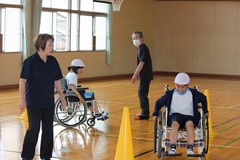 体育館で、実際に車いすに乗り動作を確認している生徒たちの写真