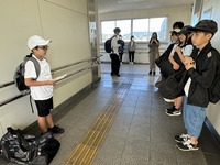 国府駅で6年生の生徒たちのグループが出発式を行っている写真
