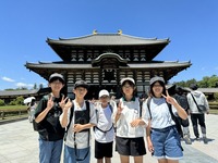 小学生5人のグループがお寺の前で記念撮影をしている写真