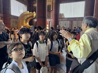小学生のグループが東大寺で大仏について説明を受けている写真