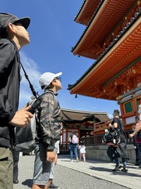 塔の前で軒下の飾りを見ている生徒の写真