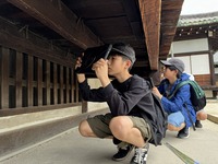 お寺の軒下に潜り込み、ウグイス張りの写真を撮っている生徒たちの写真
