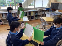 学校の教室で、生徒がペアになって答え合わせをしている写真