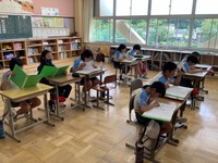 学校の教室で、生徒がペアになって音読をしている写真