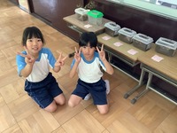 カブトムシの幼虫のケースを前にして、記念撮影をしている小学生の写真