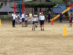 高学年の生徒が、低学年の一輪車の生徒を誘導している写真