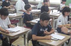 自分たちの机それぞれに置かれた資料を見ている子供たちの写真