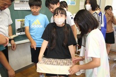 大量の偽札を重そうに持ち上げる子供の写真