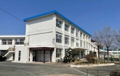 三階建ての校舎が佇んでいる右側に、葉が落ちた樹木が写っている写真