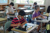 4名の生徒が教室で習字を行っている写真