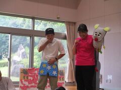 濃いピンク色の服を着た女性とその横でイラストのパンツをはいているように持っている男性の写真