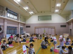 複数の親子がピンクのパンツをはいたシロクマのイラストを手に持っている写真