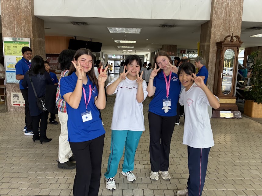 青い服を着た2人と体操服を着た2人がピースしている写真