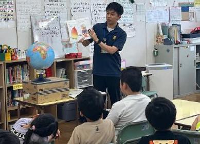 教室で大人が絵本を子どもたちに見せている写真
