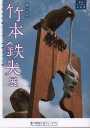 木の板にとまった鳥が人の顔の仮面を口から吊り下げている不思議なオブジェが掲載された図録の表紙