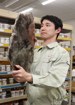 男性が大きな鉱物を両手で持ち上げて確認している写真
