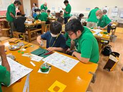 パーツの長さを測りながら切り出していく少年の写真