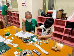 切り出したパーツを一つひとつ組み立てていく少年とそれを見守る講師の写真