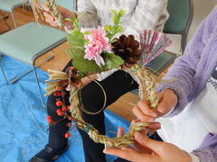 ピンクの花が飾られた藁で作ったしめ縄の写真