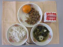 テーブルクロスに並べられた麦ごはん・牛乳・わかめスープ・いなりビビンバ・みかんの写真