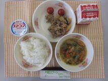 テーブルクロスに並べられたごはん・牛乳・はるさめスープ・ぶた肉のしょうが炒め・ミニトマト・ヨーグルトの写真