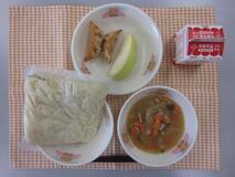 テーブルクロスに並べられた中華めん・牛乳・とんこつしょうゆラーメン・ぎょうざ・りんごの写真