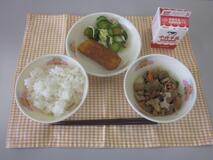 テーブルクロスに並べられたごはん・牛乳・煮しめ・いかフライのレモン煮・きゅうりあえの写真