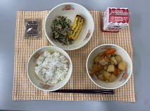 テーブルクロスに並べられたごはん・牛乳・やさいのふくめ煮・五目厚焼きたまご・赤しそあえ・ココア糖の写真