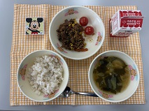 テーブルクロスに並べられた麦ごはん・牛乳・わかめスープ・ビビンバ・ミニトマト・型ぬきチーズの写真
