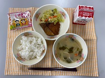 テーブルクロスに並べられたごはん・牛乳・白みそ汁・ぶりの竜田揚げ・やさいソテー・ひなあられの写真